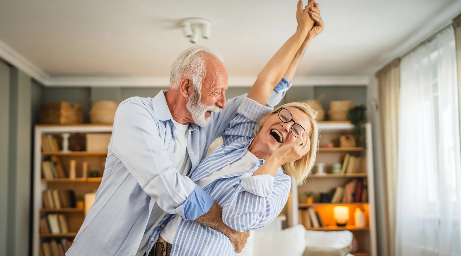 A couple dancing together at home, laughing