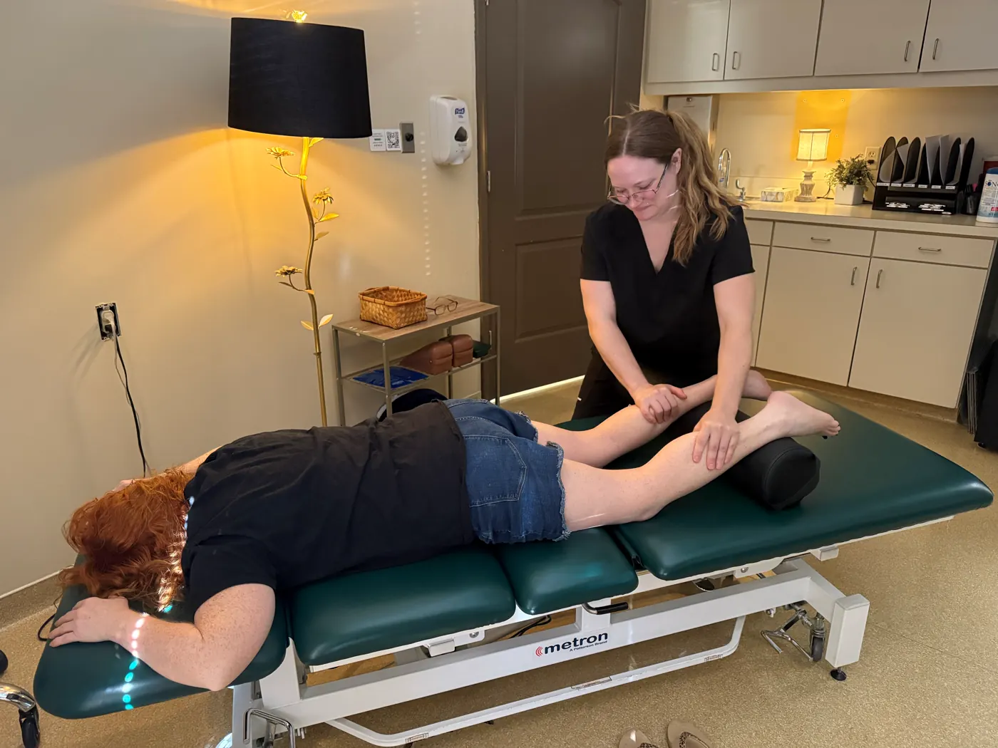 A clinician working on a patient’s lower leg as she lies face down on the treatment table