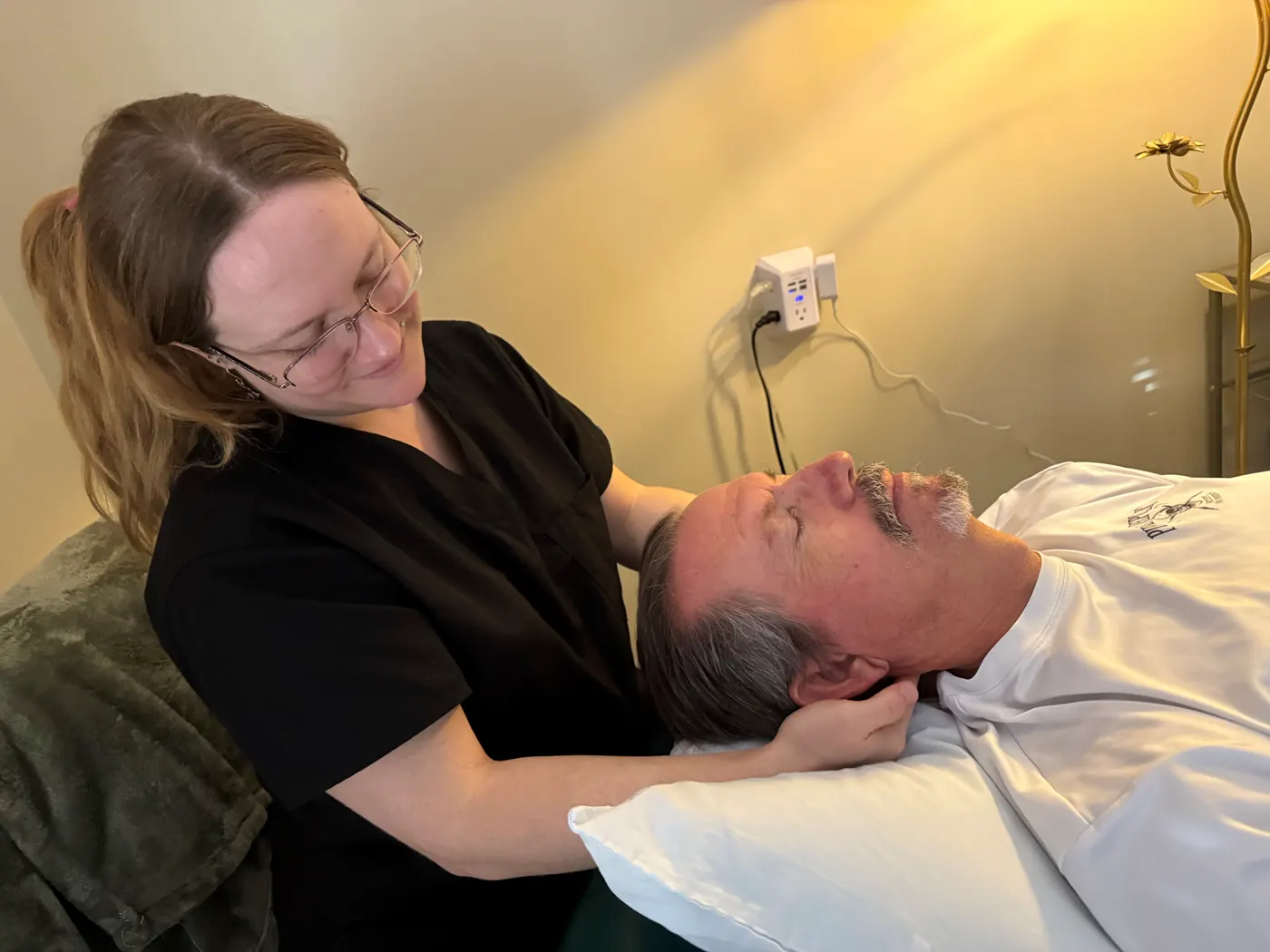 A clinician supporting a patient’s head and neck during myofascial release while he lies on the treatment table