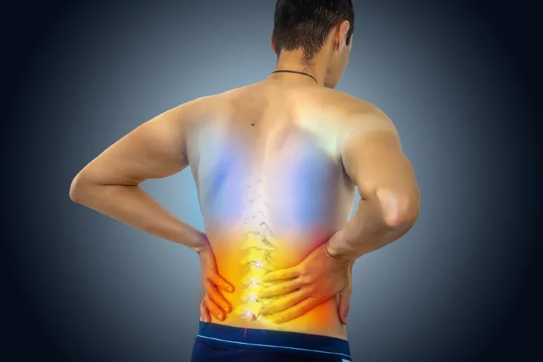 A person holding their lower back in discomfort, a common reason to seek radiculopathy treatment